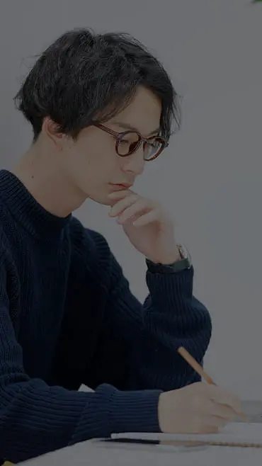 眼鏡をかけた男性がノートに思考をまとめている様子