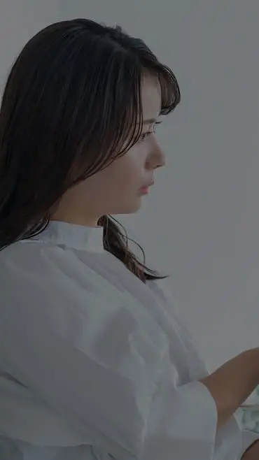 白い服を着た女性がスマートフォンを操作している様子